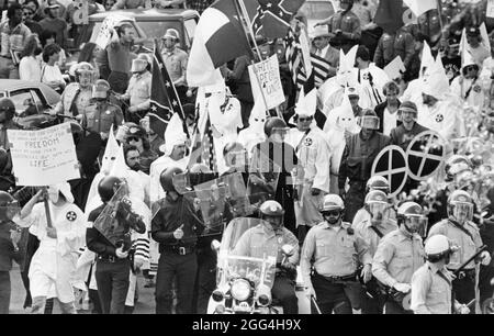 Austin, Texas, USA, um 1983: Eine kleine Gruppe von Ku Klux Klan-Mitgliedern, flankiert von der Polizei, zieht durch die Innenstadt von Austin, wo sie von einer feindlichen Anti-KKK-Menge getroffen werden. ©Bob Daemmrich Stockfoto