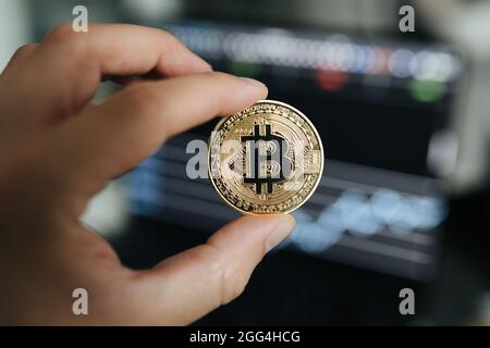 Bitcoin physische Münze Nahaufnahme zwischen zwei Fingern gehalten Stockfoto