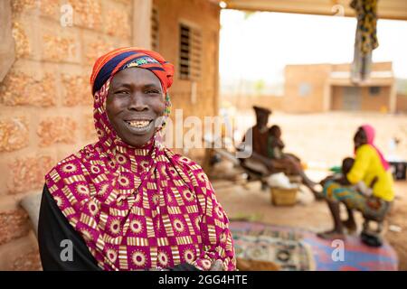 Yaoumou Arama (50) floh vor Gewalt und Unsicherheit im Nordosten von Burkina Faso und lebt heute als Binnenvertriebene in der westlichen Stadt Nouna. Yaoumou ist die alleinige Ernährerin ihrer siebenköpfigen Familie und bringt ein karges Leben ein, indem sie kocht und Snacks und Mahlzeiten an die Nachbarn verkauft. Ihr älterer Mann ist kränkeln und arbeitsunfähig. Ihre Jugendlichen und erwachsenen Kinder können keine Arbeit finden. Die Familie lebt auf einem kleinen, gemieteten Grundstück, wo man nirgendwo landwirtschaftlicher machen kann, und kämpft mit Hunger und genug Geld, um Lebensmittel zu kaufen. „Ich genieße das Leben hier nicht“, sagt sie. „Es gibt keinen Arbeitsplatz. Wenn ich hier auf der Farm wäre Stockfoto