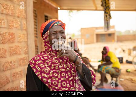 Yaoumou Arama (50) floh vor Gewalt und Unsicherheit im Nordosten von Burkina Faso und lebt heute als Binnenvertriebene in der westlichen Stadt Nouna. Yaoumou ist die alleinige Ernährerin ihrer siebenköpfigen Familie und bringt ein karges Leben ein, indem sie kocht und Snacks und Mahlzeiten an die Nachbarn verkauft. Ihr älterer Mann ist kränkeln und arbeitsunfähig. Ihre Jugendlichen und erwachsenen Kinder können keine Arbeit finden. Die Familie lebt auf einem kleinen, gemieteten Grundstück, wo man nirgendwo landwirtschaftlicher machen kann, und kämpft mit Hunger und genug Geld, um Lebensmittel zu kaufen. „Ich genieße das Leben hier nicht“, sagt sie. „Es gibt keinen Arbeitsplatz. Wenn ich hier auf der Farm wäre Stockfoto