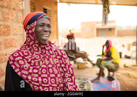 Yaoumou Arama (50) floh vor Gewalt und Unsicherheit im Nordosten von Burkina Faso und lebt heute als Binnenvertriebene in der westlichen Stadt Nouna. Yaoumou ist die alleinige Ernährerin ihrer siebenköpfigen Familie und bringt ein karges Leben ein, indem sie kocht und Snacks und Mahlzeiten an die Nachbarn verkauft. Ihr älterer Mann ist kränkeln und arbeitsunfähig. Ihre Jugendlichen und erwachsenen Kinder können keine Arbeit finden. Die Familie lebt auf einem kleinen, gemieteten Grundstück, wo man nirgendwo landwirtschaftlicher machen kann, und kämpft mit Hunger und genug Geld, um Lebensmittel zu kaufen. „Ich genieße das Leben hier nicht“, sagt sie. „Es gibt keinen Arbeitsplatz. Wenn ich hier auf der Farm wäre Stockfoto