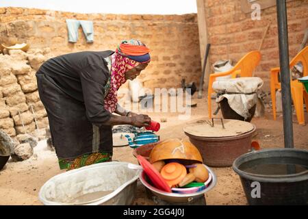 Yaoumou Arama (50) floh vor Gewalt und Unsicherheit im Nordosten von Burkina Faso und lebt heute als Binnenvertriebene in der westlichen Stadt Nouna. Yaoumou ist die alleinige Ernährerin ihrer siebenköpfigen Familie und bringt ein karges Leben ein, indem sie kocht und Snacks und Mahlzeiten an die Nachbarn verkauft. Ihr älterer Mann ist kränkeln und arbeitsunfähig. Ihre Jugendlichen und erwachsenen Kinder können keine Arbeit finden. Die Familie lebt auf einem kleinen, gemieteten Grundstück, wo man nirgendwo landwirtschaftlicher machen kann, und kämpft mit Hunger und genug Geld, um Lebensmittel zu kaufen. „Ich genieße das Leben hier nicht“, sagt sie. „Es gibt keinen Arbeitsplatz. Wenn ich hier auf der Farm wäre Stockfoto