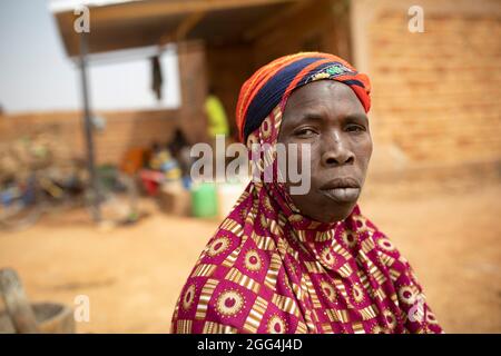 Yaoumou Arama (50) floh vor Gewalt und Unsicherheit im Nordosten von Burkina Faso und lebt heute als Binnenvertriebene in der westlichen Stadt Nouna. Yaoumou ist die alleinige Ernährerin ihrer siebenköpfigen Familie und bringt ein karges Leben ein, indem sie kocht und Snacks und Mahlzeiten an die Nachbarn verkauft. Ihr älterer Mann ist kränkeln und arbeitsunfähig. Ihre Jugendlichen und erwachsenen Kinder können keine Arbeit finden. Die Familie lebt auf einem kleinen, gemieteten Grundstück, wo man nirgendwo landwirtschaftlicher machen kann, und kämpft mit Hunger und genug Geld, um Lebensmittel zu kaufen. „Ich genieße das Leben hier nicht“, sagt sie. „Es gibt keinen Arbeitsplatz. Wenn ich hier auf der Farm wäre Stockfoto