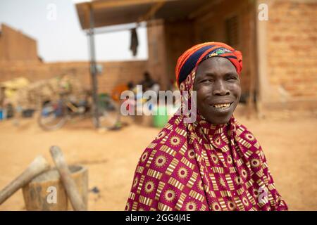 Yaoumou Arama (50) floh vor Gewalt und Unsicherheit im Nordosten von Burkina Faso und lebt heute als Binnenvertriebene in der westlichen Stadt Nouna. Yaoumou ist die alleinige Ernährerin ihrer siebenköpfigen Familie und bringt ein karges Leben ein, indem sie kocht und Snacks und Mahlzeiten an die Nachbarn verkauft. Ihr älterer Mann ist kränkeln und arbeitsunfähig. Ihre Jugendlichen und erwachsenen Kinder können keine Arbeit finden. Die Familie lebt auf einem kleinen, gemieteten Grundstück, wo man nirgendwo landwirtschaftlicher machen kann, und kämpft mit Hunger und genug Geld, um Lebensmittel zu kaufen. „Ich genieße das Leben hier nicht“, sagt sie. „Es gibt keinen Arbeitsplatz. Wenn ich hier auf der Farm wäre Stockfoto