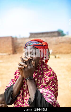 Yaoumou Arama (50) floh vor Gewalt und Unsicherheit im Nordosten von Burkina Faso und lebt heute als Binnenvertriebene in der westlichen Stadt Nouna. Yaoumou ist die alleinige Ernährerin ihrer siebenköpfigen Familie und bringt ein karges Leben ein, indem sie kocht und Snacks und Mahlzeiten an die Nachbarn verkauft. Ihr älterer Mann ist kränkeln und arbeitsunfähig. Ihre Jugendlichen und erwachsenen Kinder können keine Arbeit finden. Die Familie lebt auf einem kleinen, gemieteten Grundstück, wo man nirgendwo landwirtschaftlicher machen kann, und kämpft mit Hunger und genug Geld, um Lebensmittel zu kaufen. „Ich genieße das Leben hier nicht“, sagt sie. „Es gibt keinen Arbeitsplatz. Wenn ich hier auf der Farm wäre Stockfoto