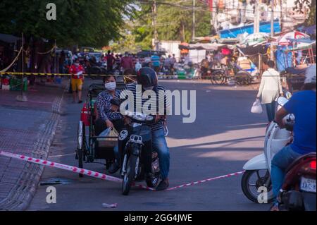 Ein Motorradfahrer schleicht sich durch eine abgesperrte Straße in der Nähe von Kandal Market. Die Straße wurde aufgrund der Delta-Variante von Covid - 19 gesperrt. Phnom Penh, Kambodscha. August 2021. © Kraig Lieb Stockfoto