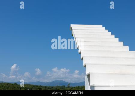 Eine weiße Holztreppe oder Leiter führt zu einem blauen Himmel mit hellen malerischen Hintergrund Berge. Stockfoto