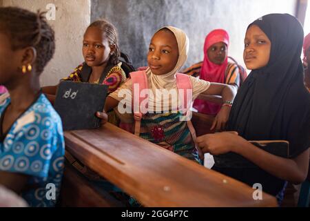 Das Senou Camp liegt am südlichen Rand von Bamako, Malis Hauptstadt. Es ist eines von acht solchen informellen Camps in der ganzen Stadt und allein beherbergt es 223 Familien und etwas mehr als 1.000 Binnenvertriebene. Die hier lebenden Familien sind vor Gewalt und Aufstand im Norden und in den zentralen Teilen des Landes geflohen. Da die meisten von ihnen kein Einkommen oder eine regelmäßige Nahrungsquelle haben, ist der Hunger eine tägliche Herausforderung und die Unterernährung der Bevölkerung ist nach wie vor weit verbreitet. Hier schreiben Kinder auf Kreideschiefer in der einzigen Grundschule des Lagers, die von Frau Asmatou Coulibably unterrichtet wurde. Stockfoto