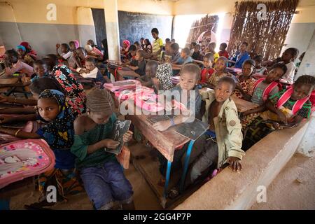 Das Senou Camp liegt am südlichen Rand von Bamako, Malis Hauptstadt. Es ist eines von acht solchen informellen Camps in der ganzen Stadt und allein beherbergt es 223 Familien und etwas mehr als 1.000 Binnenvertriebene. Die hier lebenden Familien sind vor Gewalt und Aufstand im Norden und in den zentralen Teilen des Landes geflohen. Da die meisten von ihnen kein Einkommen oder eine regelmäßige Nahrungsquelle haben, ist der Hunger eine tägliche Herausforderung und die Unterernährung der Bevölkerung ist nach wie vor weit verbreitet. Hier lernen die Kinder in der einzigen Grundschule des Lagers, die von Frau Asmatou Coulibably unterrichtet wird. Stockfoto