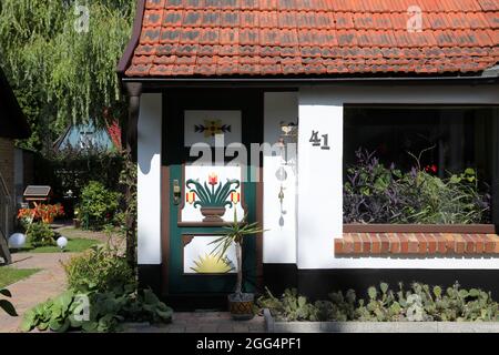 Prerow, Deutschland. August 2021. Eine Darß-Tür auf einem Haus. Die ursprünglichen Darß-Türen wurden zwischen 1790 und 1850 geschaffen, typisch sind geschnitzte Ornamente mit Bezug auf die Seefahrt oder die Natur. Die Türen gehörten zu den repräsentativen Häusern der damaligen Seeleute, die es zu einem gewissen Wohlstand gebracht hatten. Quelle: Bernd Wüstneck/dpa-Zentralbild/ZB/dpa/Alamy Live News Stockfoto