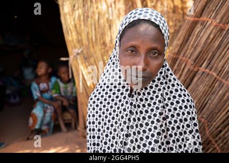 Das Senou Camp liegt am südlichen Rand von Bamako, Malis Hauptstadt. Es ist eines von acht solchen informellen Camps in der ganzen Stadt und allein beherbergt es 223 Familien und etwas mehr als 1.000 Binnenvertriebene. Die hier lebenden Familien sind vor Gewalt und Aufstand im Norden und in den zentralen Teilen des Landes geflohen. Da die meisten von ihnen kein Einkommen oder eine regelmäßige Nahrungsquelle haben, ist der Hunger eine tägliche Herausforderung und die Unterernährung der Bevölkerung ist nach wie vor weit verbreitet. Hier sitzt Fatima Bolly (33) vor ihrem provisorischen Tierheim. Stockfoto