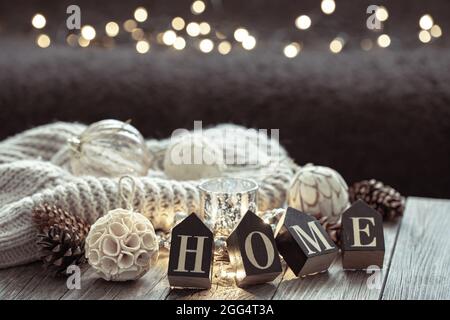 Nahaufnahme von Holzbuchstaben machen das Wort zu Hause, Details der Weihnachtsdekoration auf verschwommenem Hintergrund mit Bokeh. Stockfoto