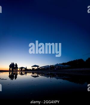 Silhouetten der Menge an der Strandbar während des Sonnenuntergangs Stockfoto