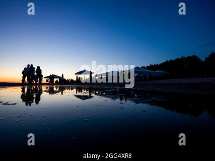 Silhouetten der Menge an der Strandbar während des Sonnenuntergangs Stockfoto