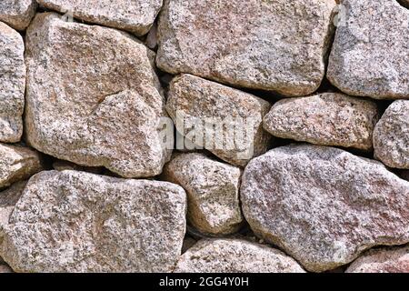 Wand mit grauen und braunen unregelmäßigen unterschiedlich großen und geformten Steinen Stockfoto