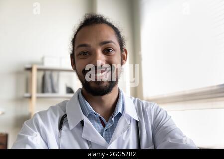Lächelnder, freundlicher junger afroamerikanischer Arzt, der ein Videogespräch führt. Stockfoto