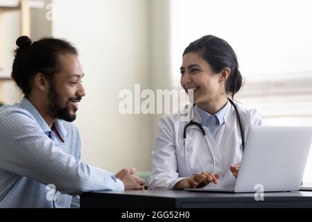 Glücklicher, tausendjähriger afroamerikanischer Patient im Gespräch mit einem indischen Arzt. Stockfoto