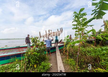 Munshiganj, Bangladesch. August 2021. Arbeiter tragen Holzteile aus einem beschädigten Haus, da die Erosion des Flusses Padma die Betonstrukturen in Tongibari, Munshiganj, am Stadtrand von Dhaka, weiter wegspült.nach dem Monsun haben sich gewaltsame Erosionen in die Ufer des Padma-Flusses gefressen, die große Teile in Munshiganj, Tongibari Upazila, Bangladesch, bedrohten. (Foto von Nayan Kar/SOPA Images/Sipa USA) Quelle: SIPA USA/Alamy Live News Stockfoto