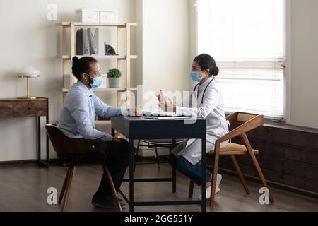 Konzentrierter junger afrikanischer Patient im Gespräch mit einem indischen Arzt. Stockfoto