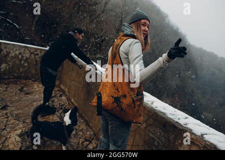 Junges Paar beim Spaziergang mit Corgi-Hund im Winterpark. Stockfoto