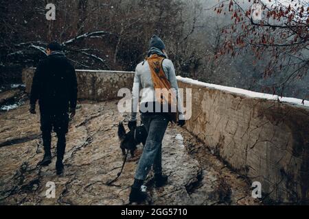 Junges Paar beim Spaziergang mit Corgi-Hund im Winterpark. Stockfoto