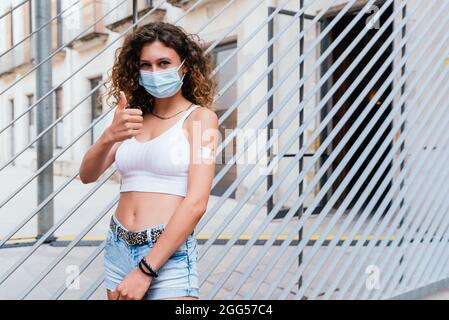 Horizontales Porträt einer kaukasischen jungen Frau, die nach der Impfung mit dem Finger eine positive Geste machte 19 Stockfoto