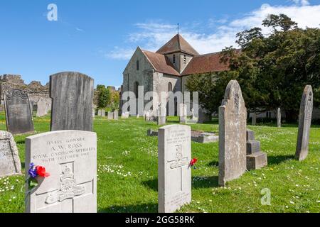 Die Kirche St. Mary aus dem 12. Jahrhundert, im äußeren bailey von Portchester Castle: Friedhof und nahe gelegene Mauern des ursprünglichen römischen Forts, Hampshire, Großbritannien Stockfoto