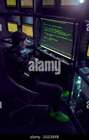 Hacker arbeitet mit Computer, der Text in einem dunklen Raum eingibt. Datensicherheitskonzept. Stockfoto
