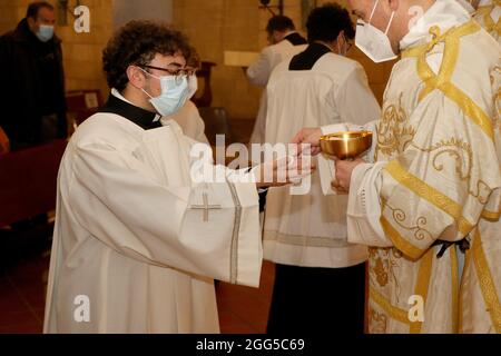 Kommunion Ritus während der Messe in einer katholischen Kirche. Priester geben Gastgeber in den Händen eines Gläubigen Stockfoto