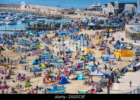 Lyme Regis, Dorset, Großbritannien. August 2021. Wetter in Großbritannien: Urlauber und Familien strömen an den beliebten Strand am Badeort Lyme Regis, um am Feiertagswochenende die glühend heiße Sonne und den klaren blauen Himmel zu genießen. Angesichts des herrlichen Sonnenwetters, das bis zum Montag an den Bankfeiertagen andauern wird, werden die Strände und Resorts an der Südküste voraussichtlich noch stärker überfüllt sein als sonst, da in diesem Sommer mehr Menschen in Großbritannien Urlaub machen. Der Kredit: Celia McMahon/Alamy Live Nachrichten Stockfoto
