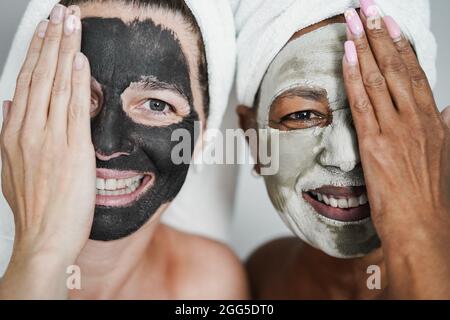 Multirassische ältere Frauen, die Schönheitsbehandlungen mit Hautmaske machen - Körperpflegekonzept - Fokus auf das rechte weibliche Gesicht Stockfoto