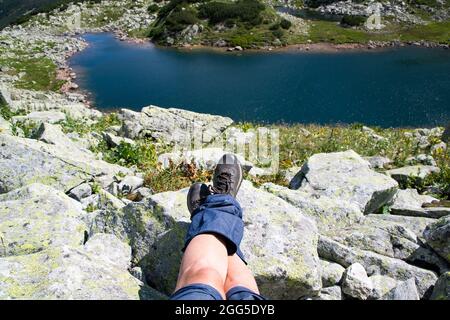 Frauenbeine mit Trekkingstiefeln über dem Gletschersee in den Bergen Freiheit und Slow Travel Konzept Stockfoto