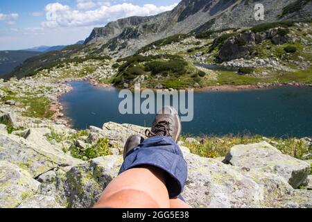 Frauenbeine mit Trekkingstiefeln über dem Gletschersee in den Bergen Freiheit und Slow Travel Konzept Stockfoto