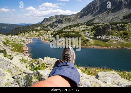 Frauenbeine mit Trekkingstiefeln über dem Gletschersee in den Bergen Freiheit und Slow Travel Konzept Stockfoto