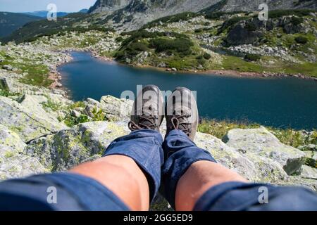 Frauenbeine mit Trekkingstiefeln über dem Gletschersee in den Bergen Freiheit und Slow Travel Konzept Stockfoto