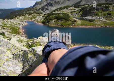 Frauenbeine mit Trekkingstiefeln über dem Gletschersee in den Bergen Freiheit und Slow Travel Konzept Stockfoto