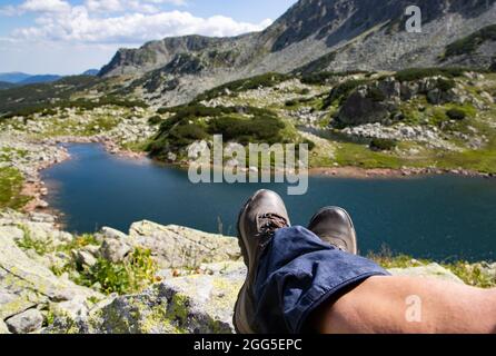 Frauenbeine mit Trekkingstiefeln über dem Gletschersee in den Bergen Freiheit und Slow Travel Konzept Stockfoto