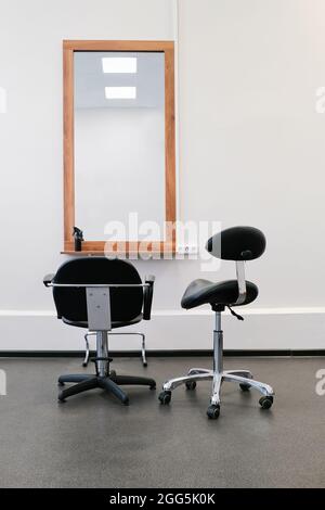 Friseursessel und Spiegel bereit, Besucher zu empfangen. Das Innere des Salons mit Friseurausrüstung und Möbeln. Stockfoto