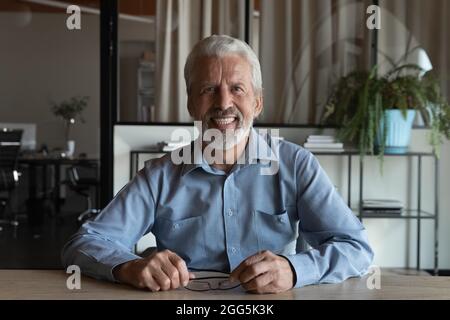 Porträt eines lächelnden, reifen Geschäftsmannes, der Videoanruf abgibt Stockfoto