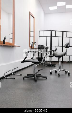 Friseure Stuhl und Spiegel bereit, Besucher zu empfangen. Das Innere des Salons mit Friseurausrüstung und Möbeln. Stockfoto