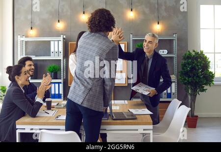 Gruppe von multinationalen Geschäftsmitarbeitern, die lächeln, glücklich und selbstbewusst sind und die Hände berühren Stockfoto