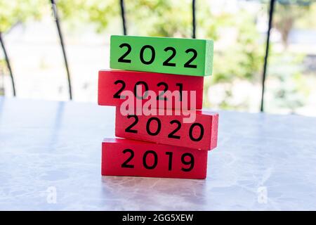 Die Worte 2019, 2020, 2021 und 2022 stehen auf den übereinander gestapelten Holzblöcken. Neues Jahr 2022 kommt Konzept.
