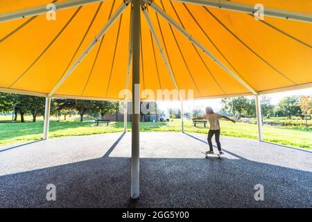 Carrigaline, Cork, Irland. August 2021. Joshua O Drisceoil skates under the Canopy of the New Bandstand at the Community Park in Carrigaline, Co. Cork, Ireland. - Credit: David Creedon / Alamy Live News Stockfoto