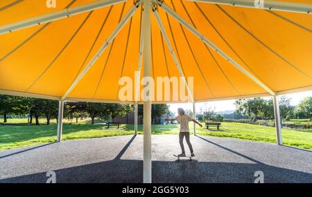 Carrigaline, Cork, Irland. August 2021. Joshua O Drisceoil skates under the Canopy of the New Bandstand at the Community Park in Carrigaline, Co. Cork, Ireland. - Credit: David Creedon / Alamy Live News Stockfoto