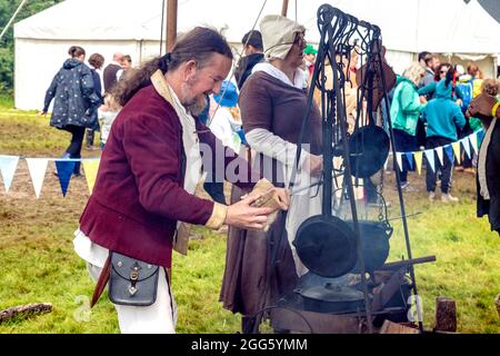 8. August 2021 - ein Mann, der ein Stück Fleisch auf den Bratspieß in der mittelalterlichen Küche (Jane’s Medieval Kitchen) beim Medieval Festival Loxwood J stielt Stockfoto