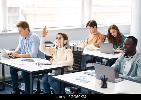 Porträt einer lächelnden Schülerin, die im Klassenzimmer die Hand hebt Stockfoto