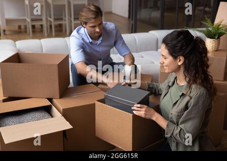 Glückliches junges Familienpaar, das Kartons auspackt. Stockfoto