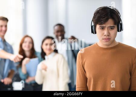 Die Leute spotten und machen sich über traurigen asiatischen Mann lustig Stockfoto