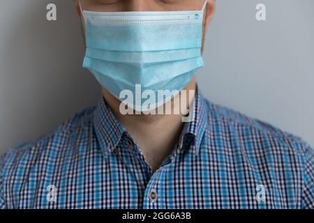 Junger kaukasischer Mann in lässiger Kleidung mit medizinischer Maske im Gesicht Stockfoto