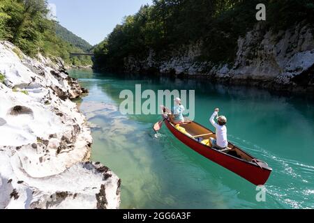 Mutter und Sohn rudern in einem roten Kanu auf dem Fluss Soca in der Nähe von Most na Soci, Avce, Slowenien Stockfoto